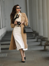 A lady wears a trench coat and a denim skirt.